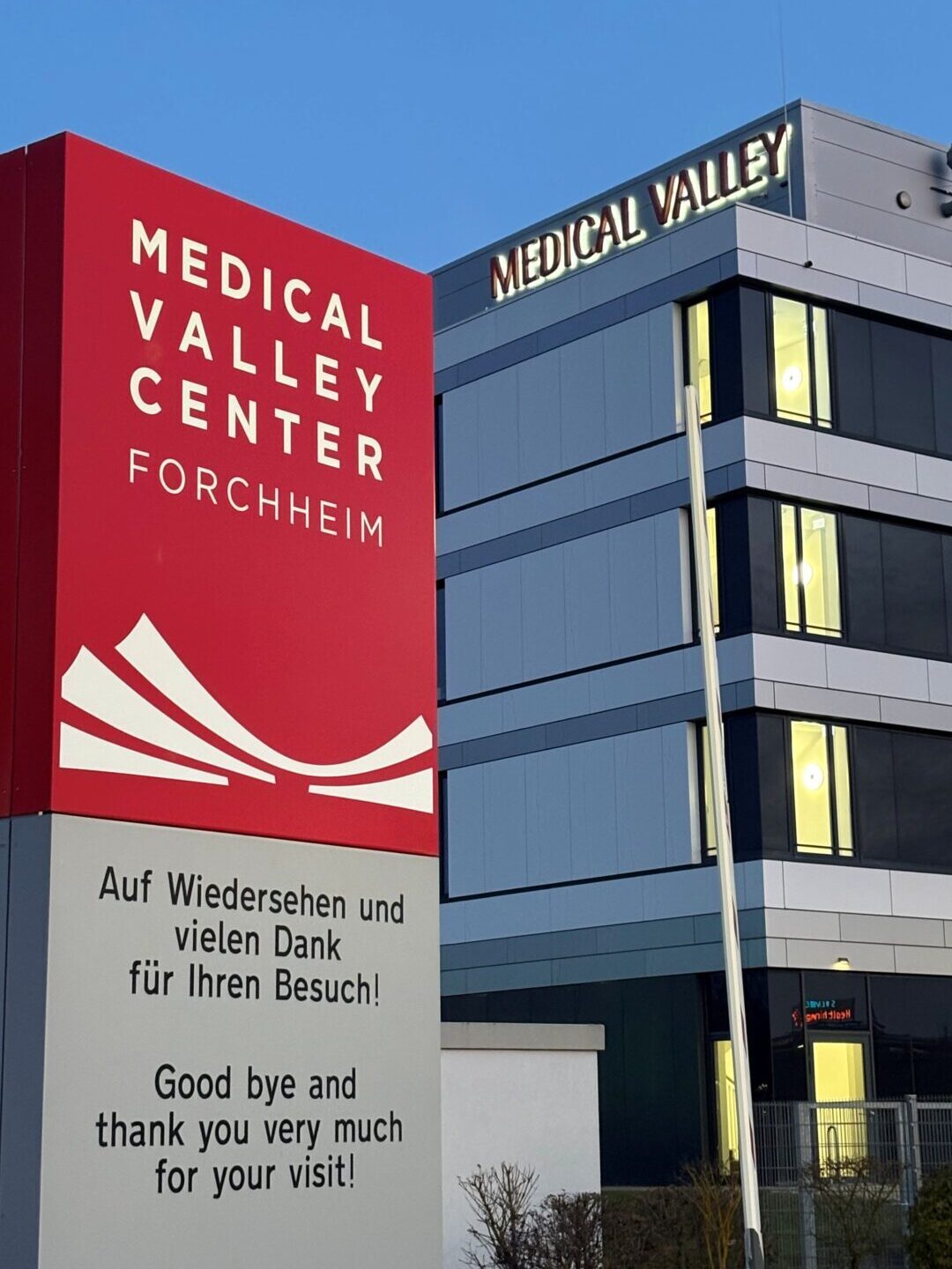 Exterior view of the Medical Valley Center Forchheim—with a large red sign and modern office building against a blue sky.